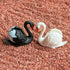 Close-up of black and white swan figurines in red Zen garden sand