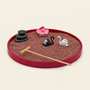 Red oval Zen garden with red sand, stacked stones, lotus, black and white swans, and bamboo rake