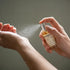 Person using Portable Chakra Aromatherapy Mist for Yoga & Deep Meditation -10ml on wrist for relaxation.