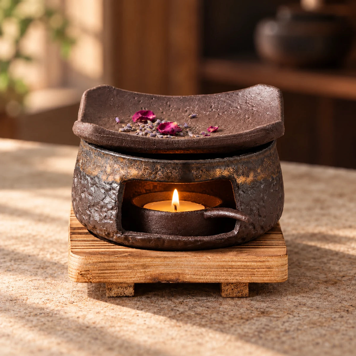 Textured brown ceramic warmer and curved dish with lavender and rose petals, a small lit tealight in the chamber, and a wooden base.